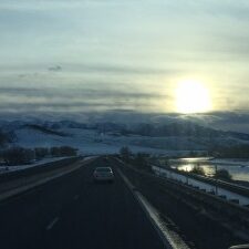 Snowy road with sunset and mountains.