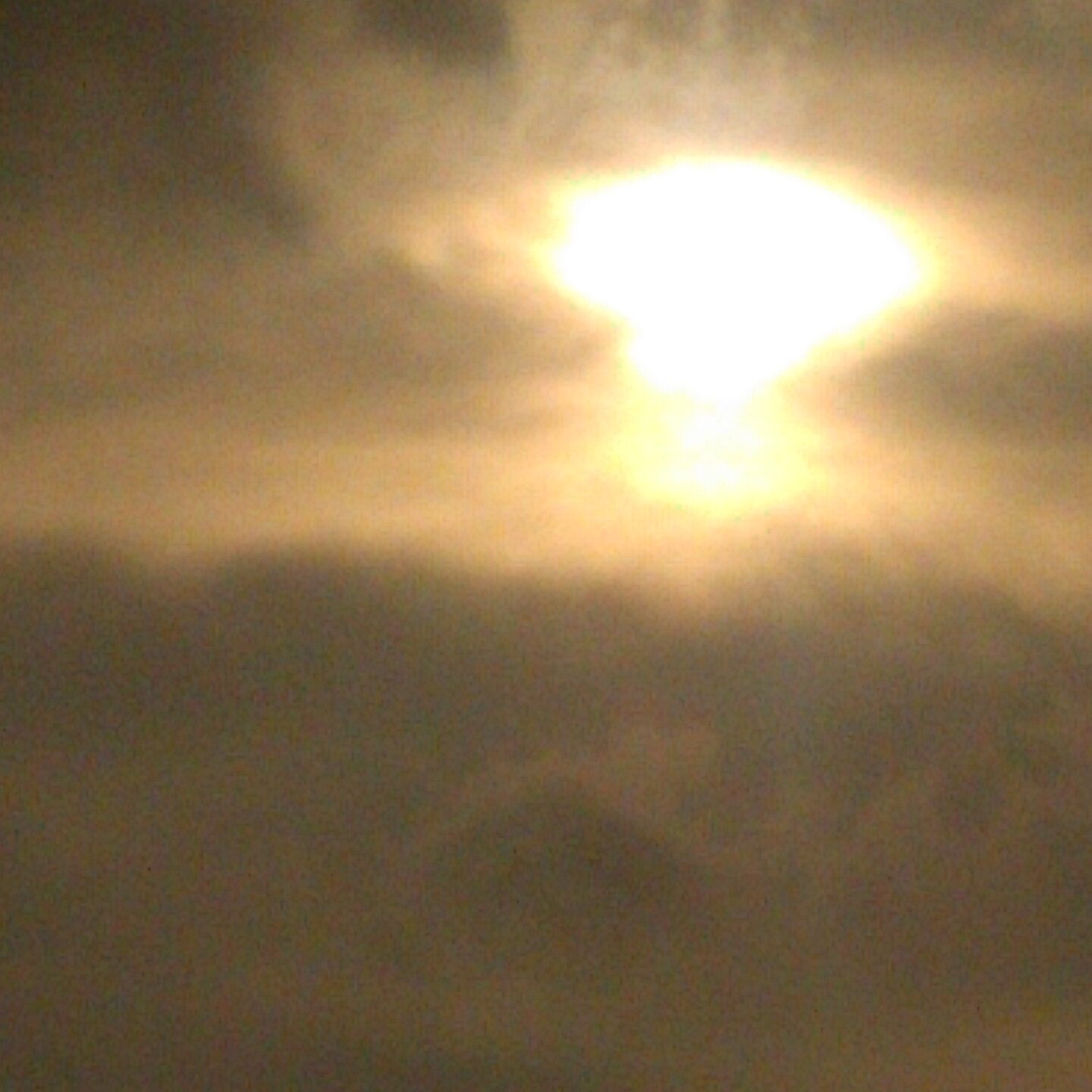 Bright sun shining through cloudy sky.