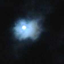 Moon shining through cloudy night sky.