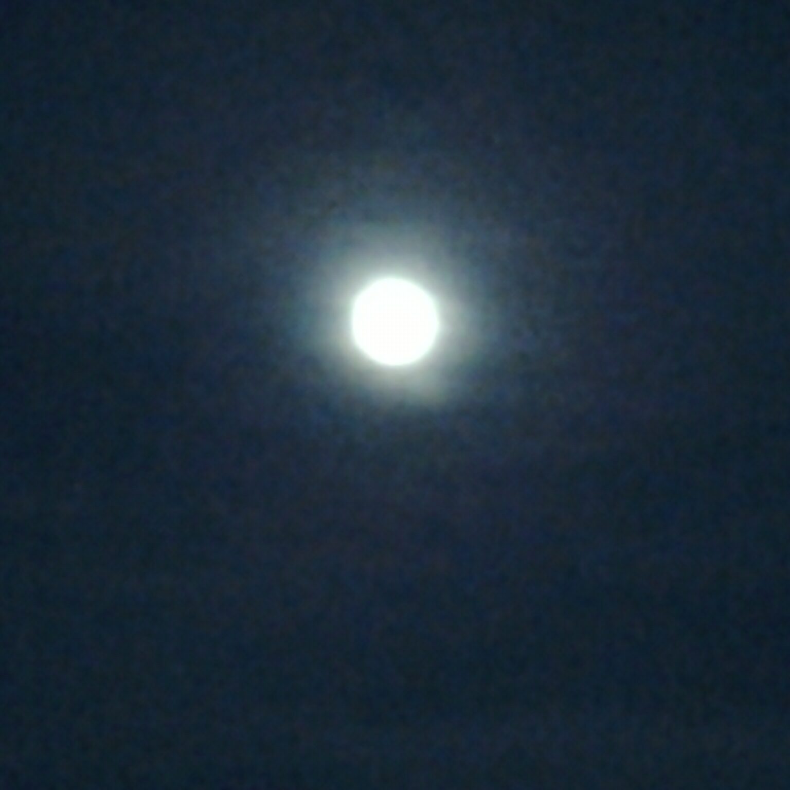 Blurry full moon in dark night sky.