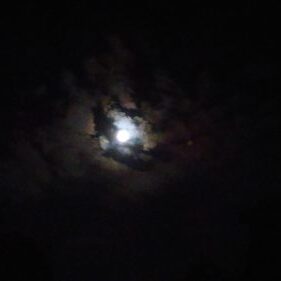 Moon shining through dark night clouds.