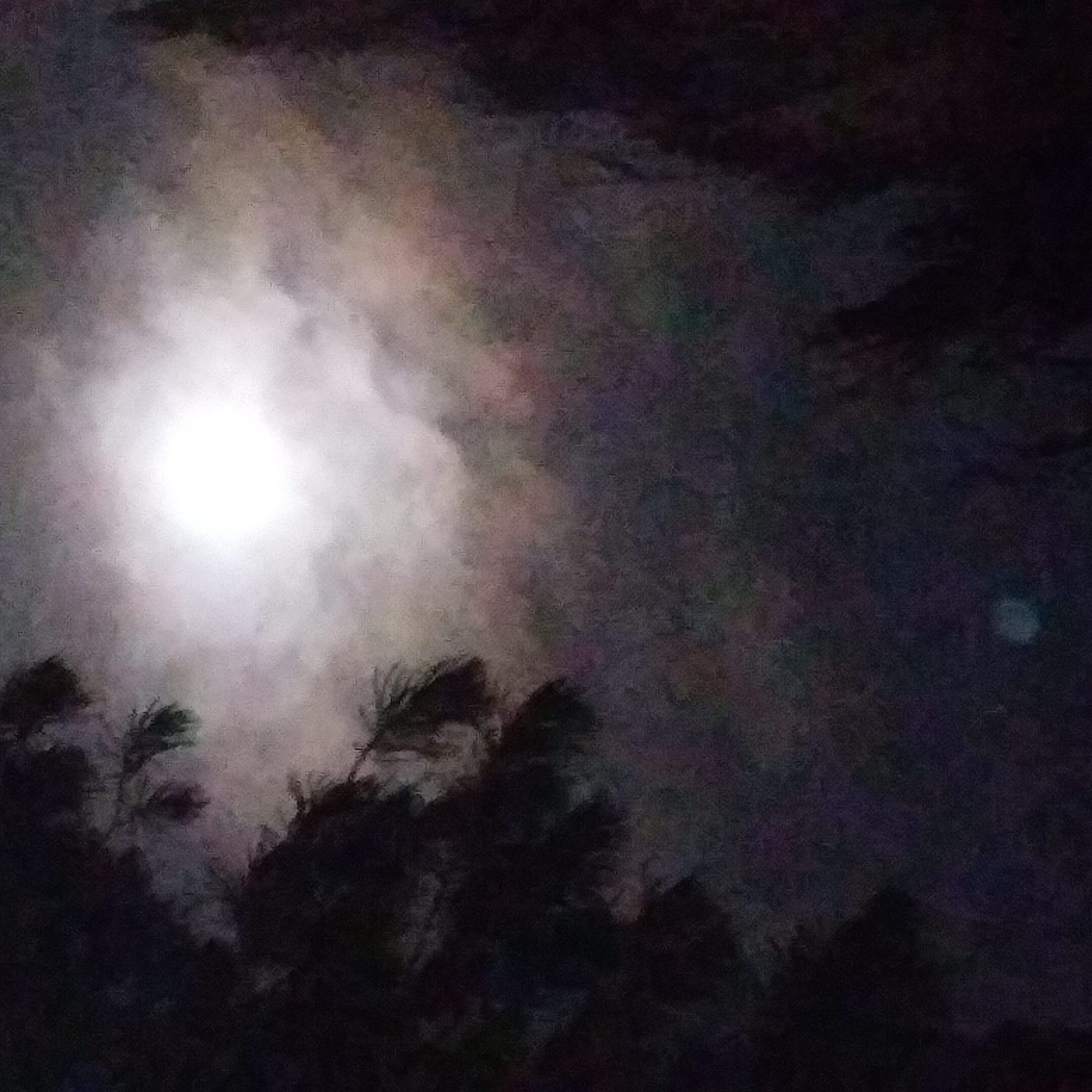 Moon shining through cloudy night sky.