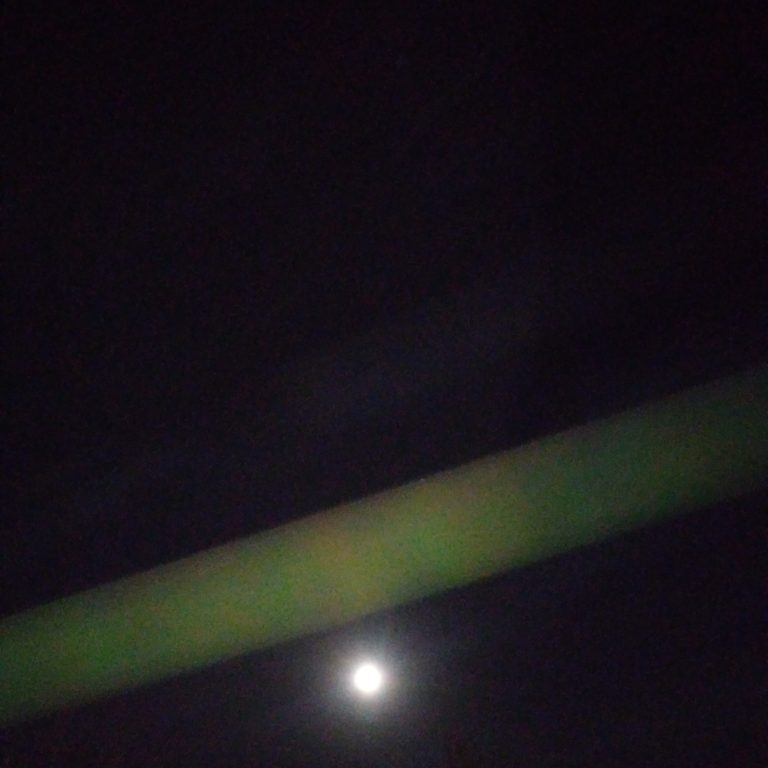 Night sky with moon and green light.