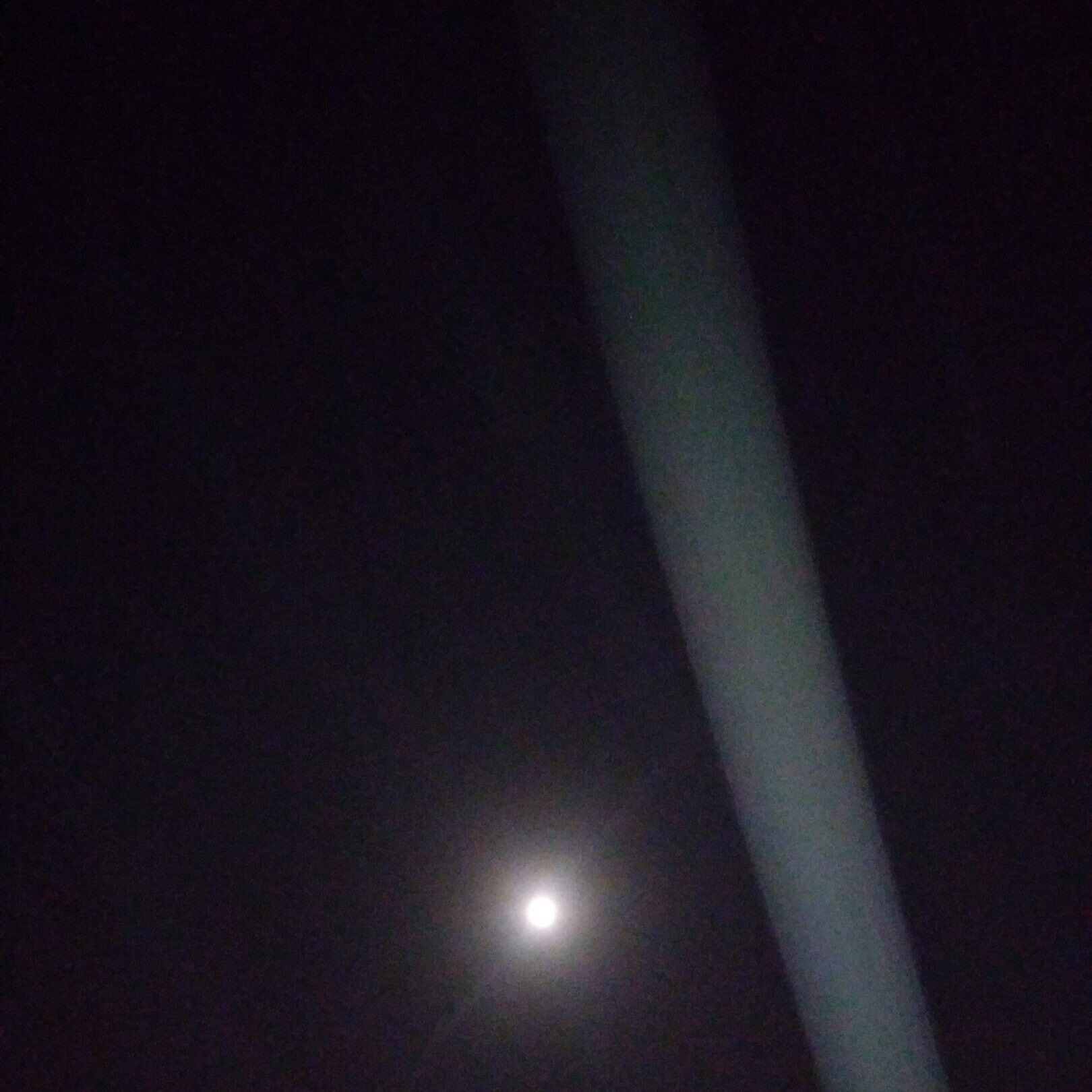 Moon shining in dark night sky, light beam.