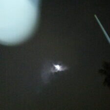 Moon in cloudy night sky, blurred foreground.