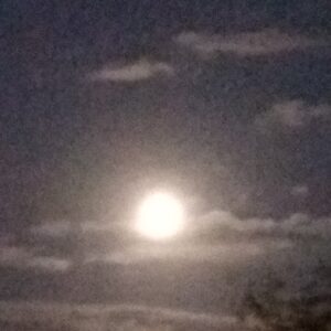 Full moon glowing behind scattered clouds.