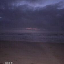 Dark beach at twilight with cloudy sky.