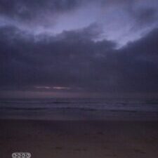 Dark beach scene with cloudy sky.