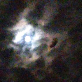 Moon shining through a cloudy night sky.