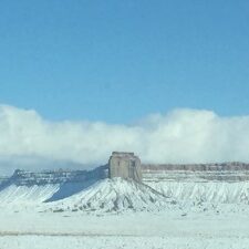 Snow-covered mesa under a clear blue sky.