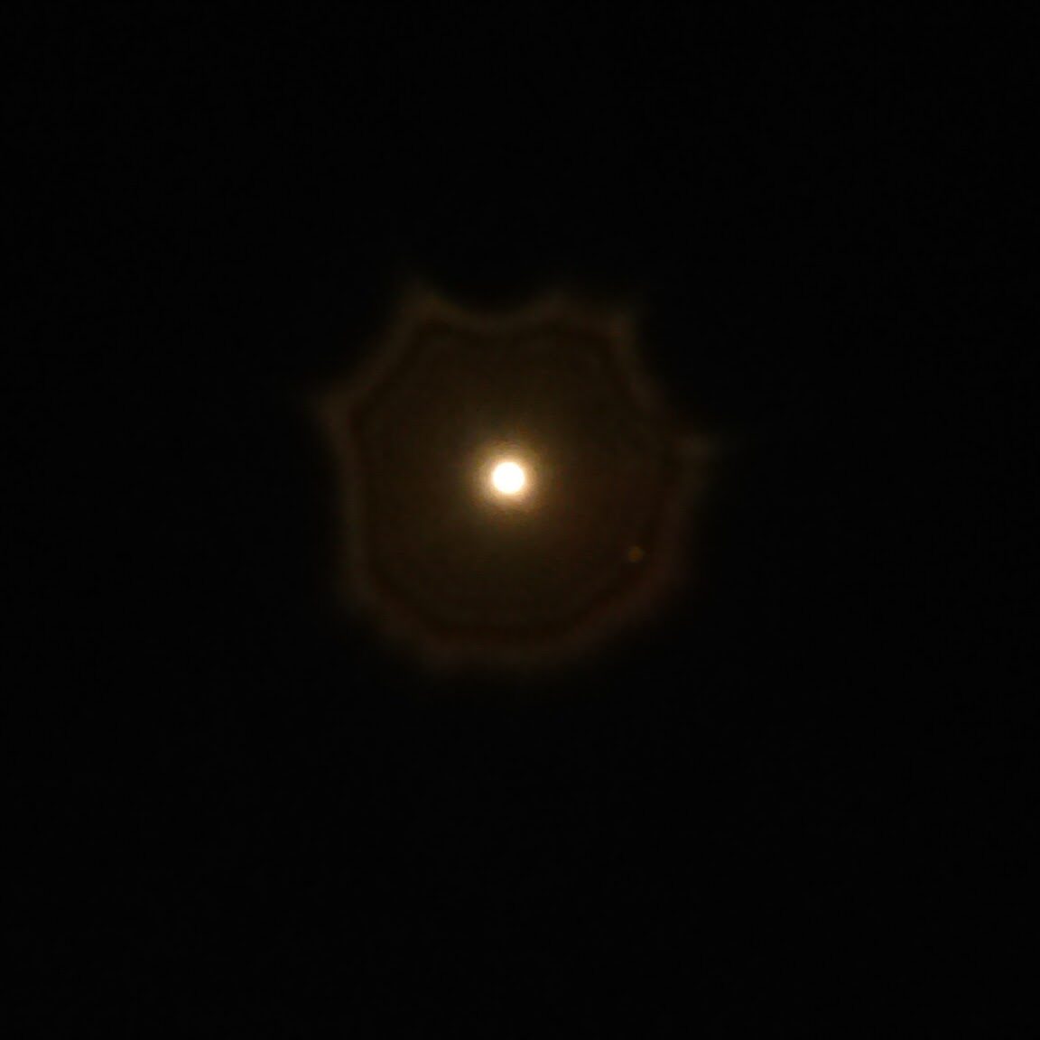 Bright light with circular halo in darkness.