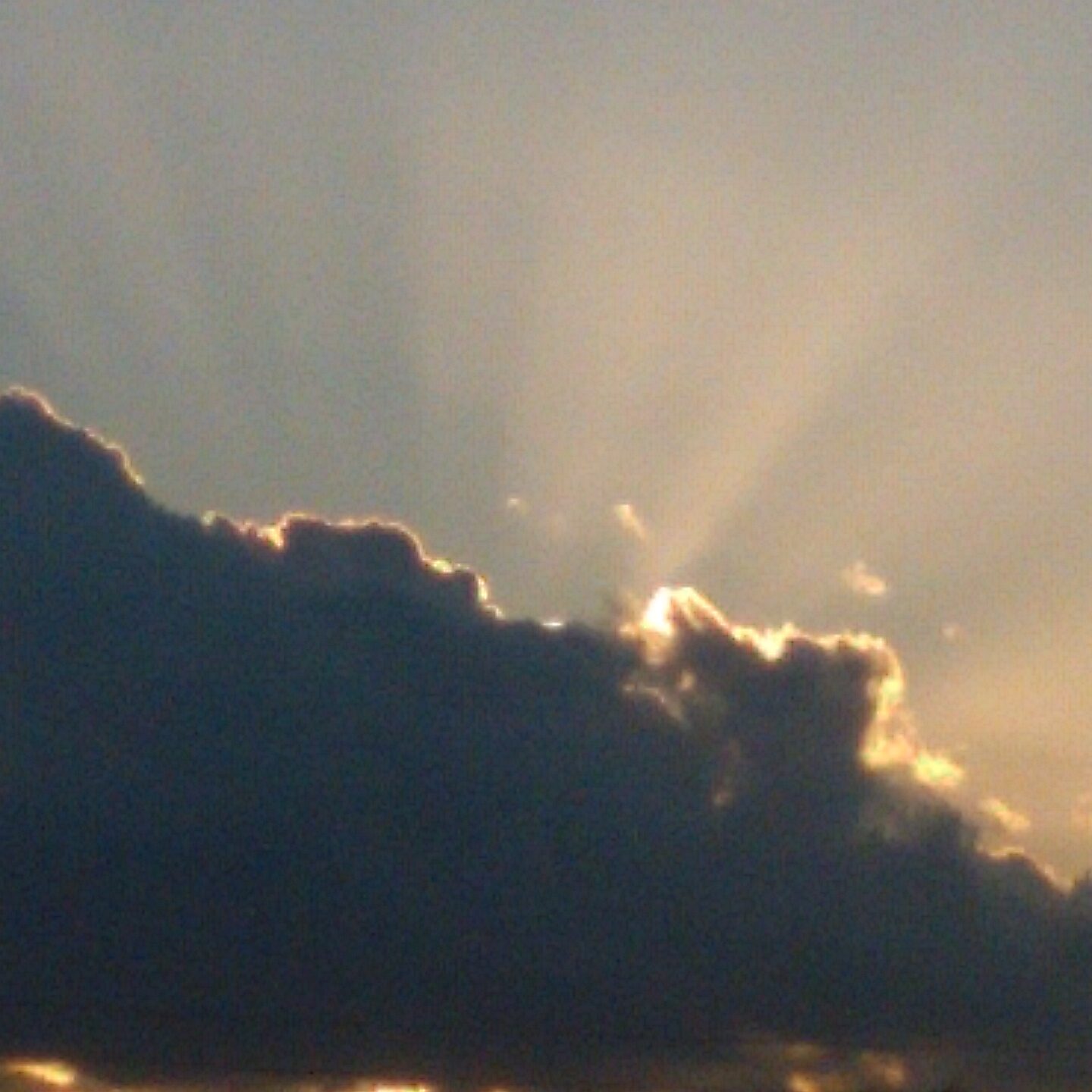 Sun rays emerging from behind dark clouds.