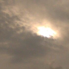 Cloudy sky with sun partially obscured.