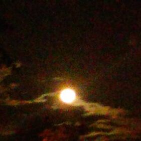 Bright moon in a cloudy night sky.