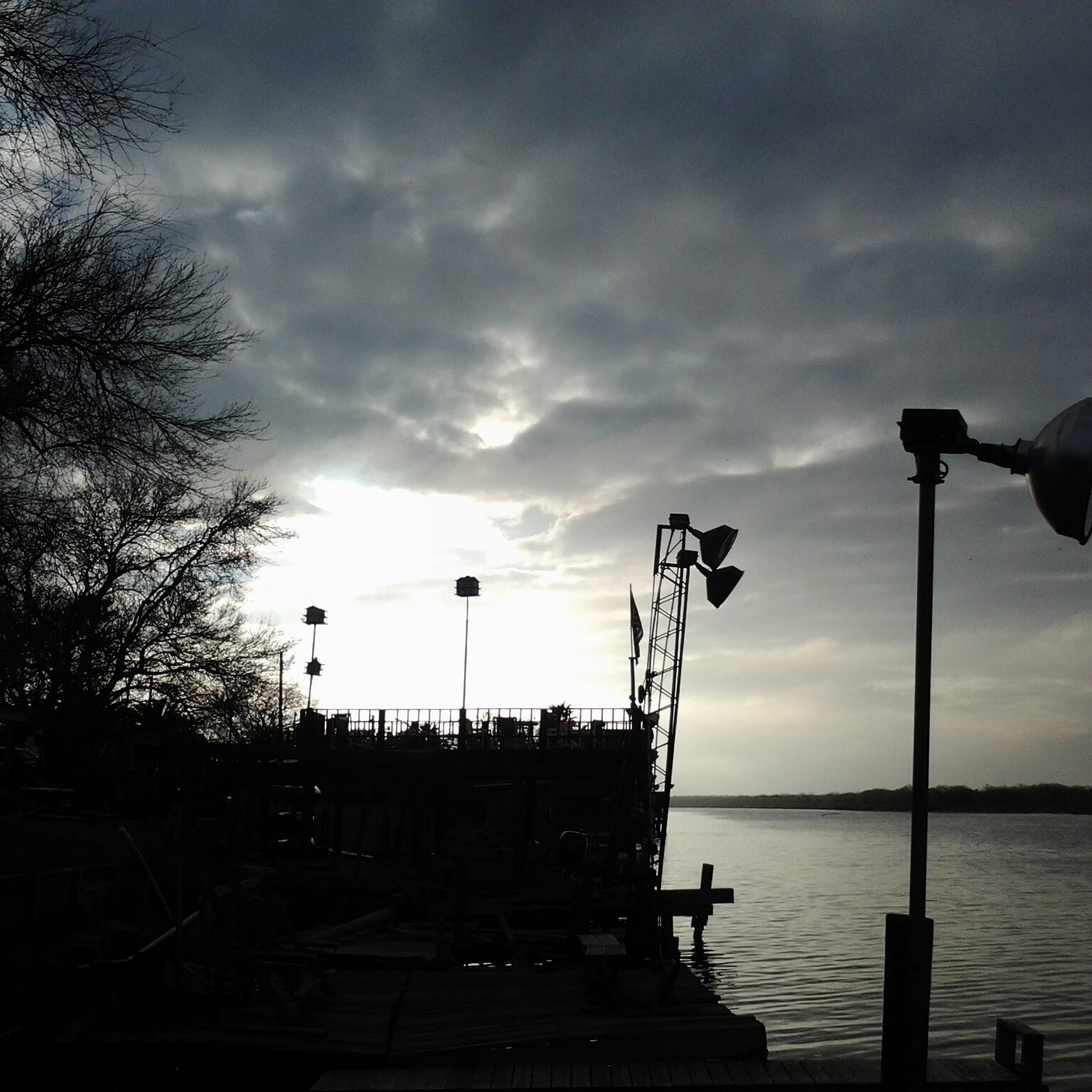 Silhouetted dock and trees at sunset.