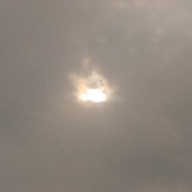 Sun shining through overcast cloudy sky.