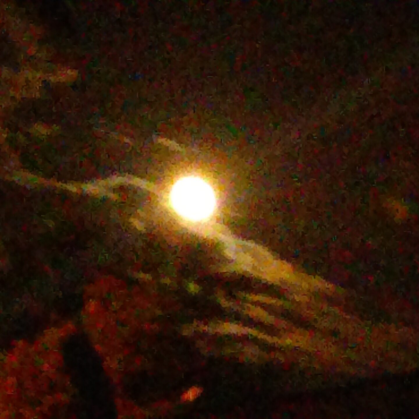 Bright moon obscured by dark clouds.