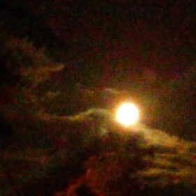 Full moon surrounded by dark clouds.