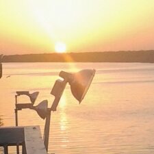 Sunset over calm water with lamp.