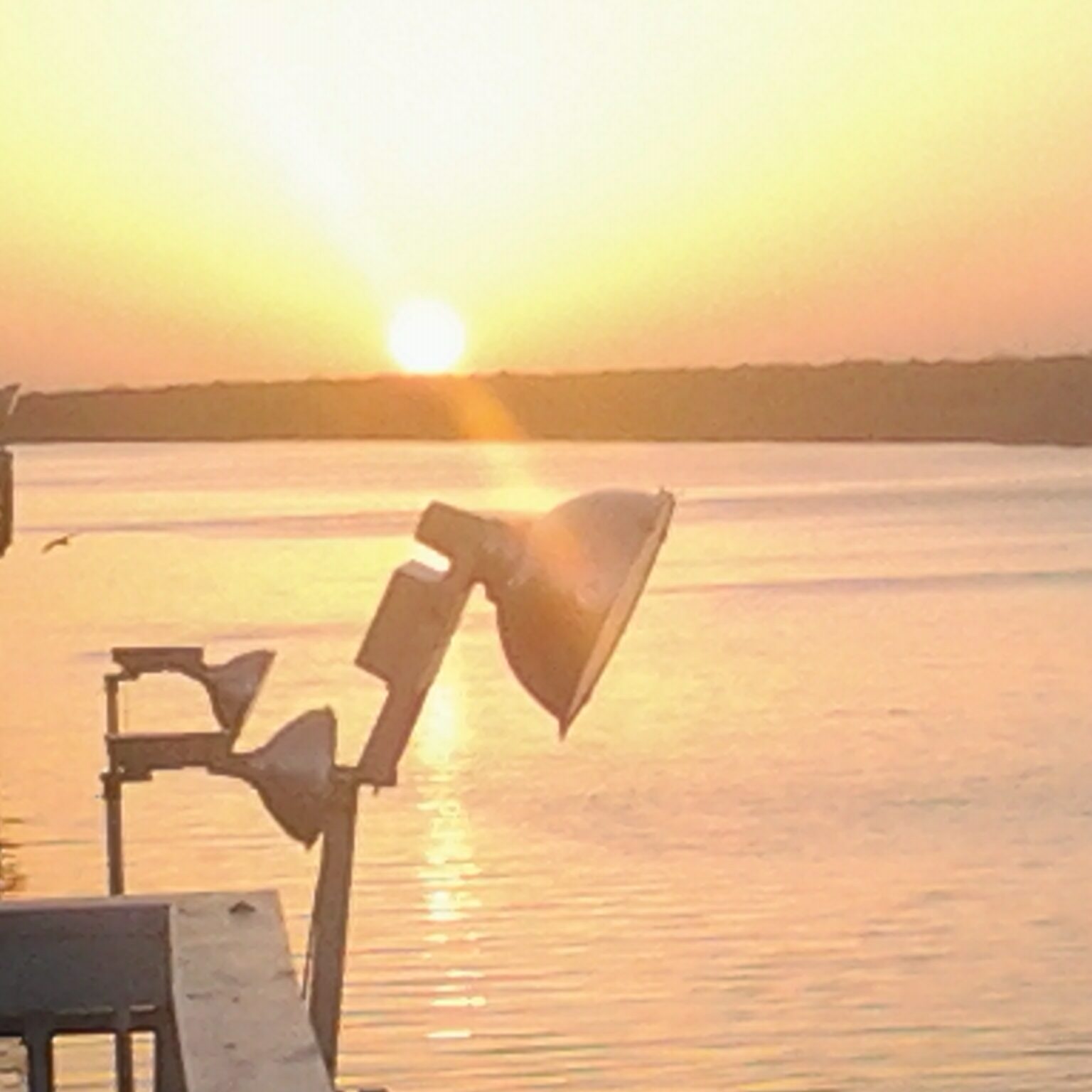 Sunset over calm water with dock.