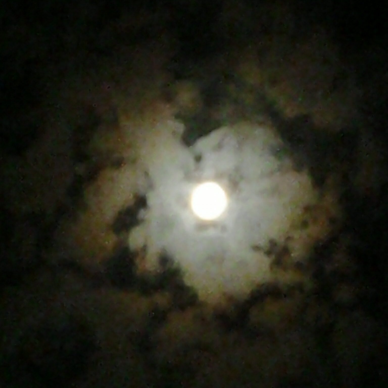 Full moon surrounded by clouds at night.