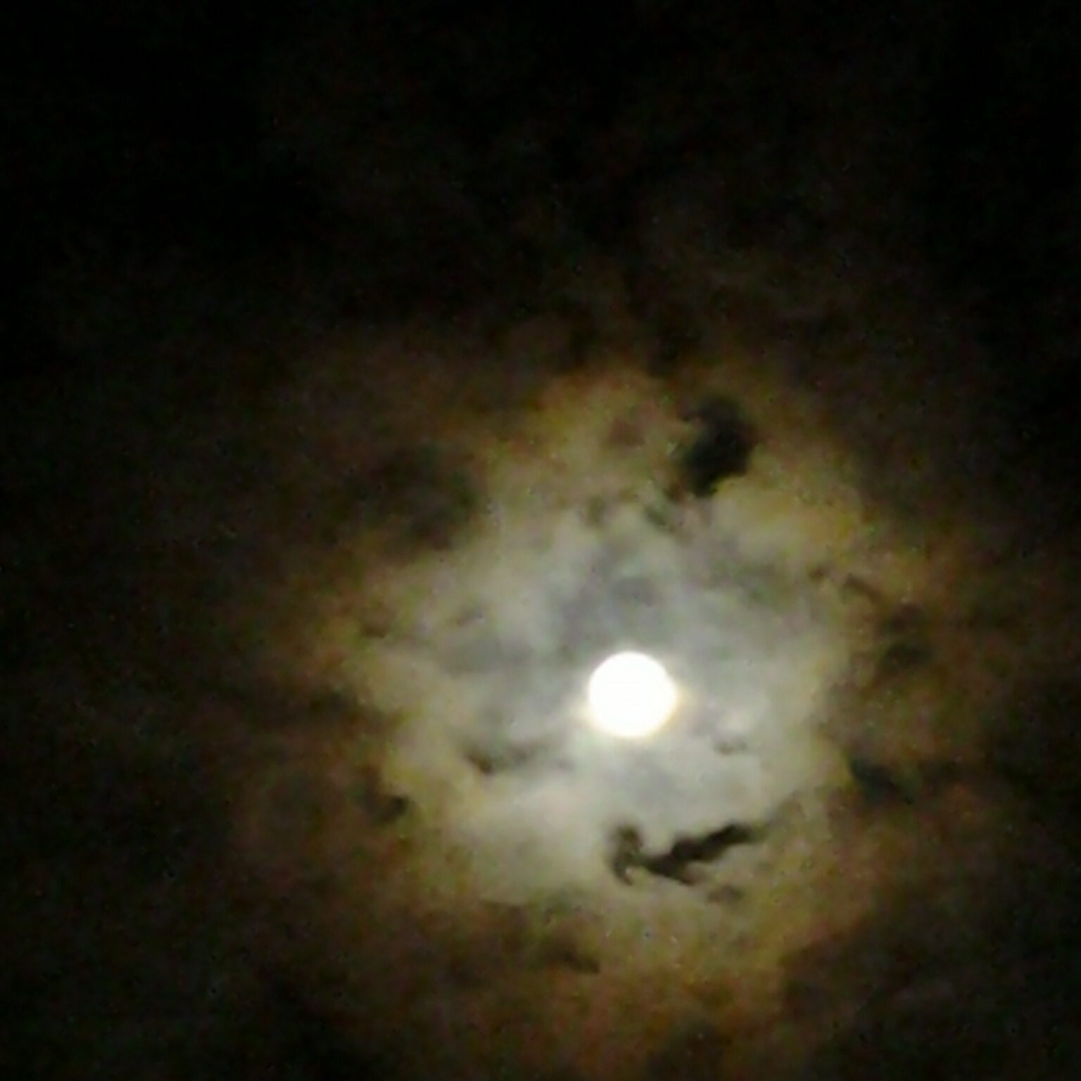 Full moon surrounded by dark, cloudy sky.