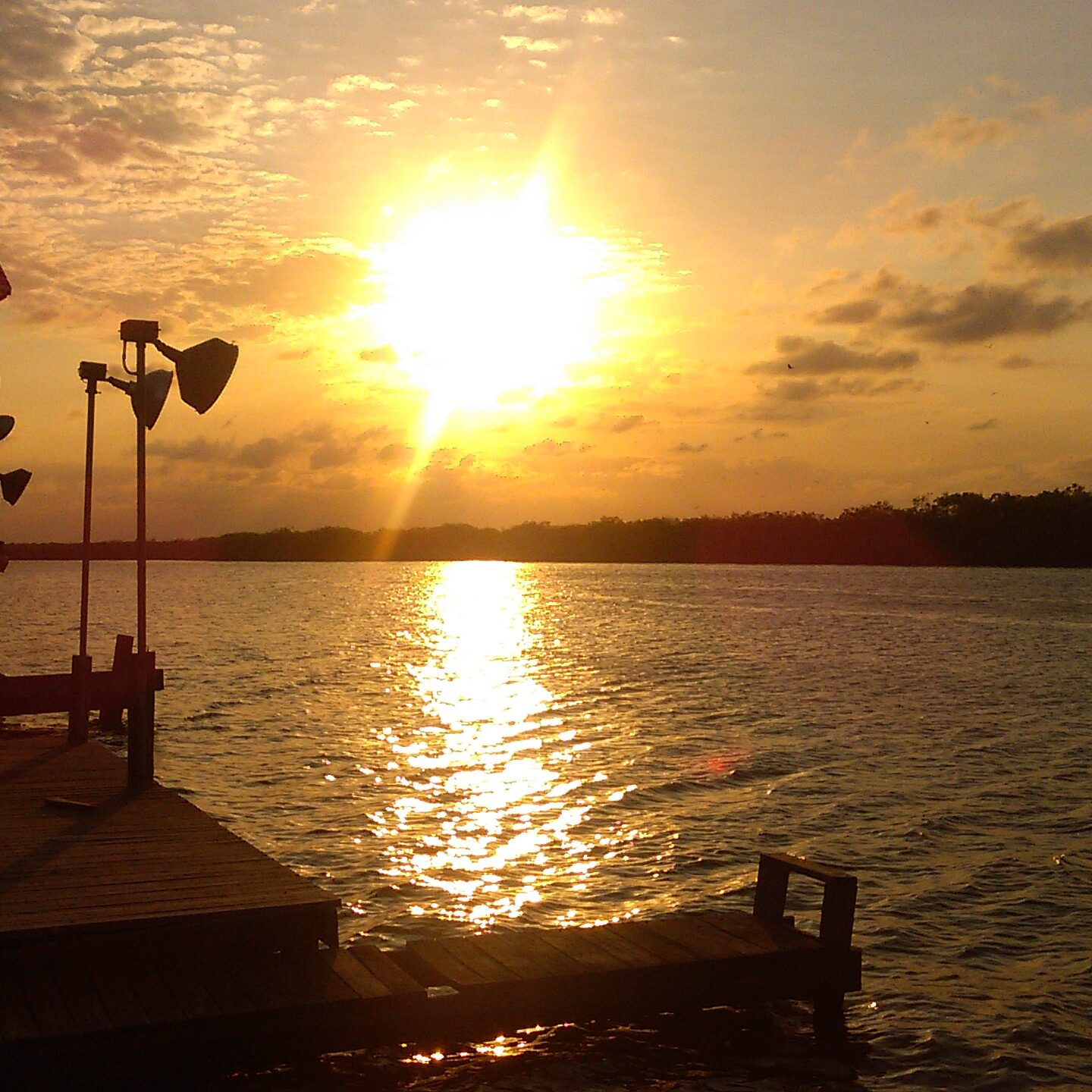 Sunset over calm lake with dock.