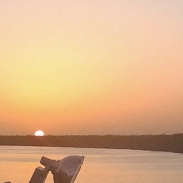 Sunset over calm lake with clear sky.