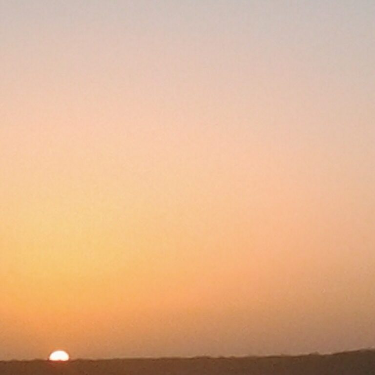 Sunset over a distant, dark horizon.