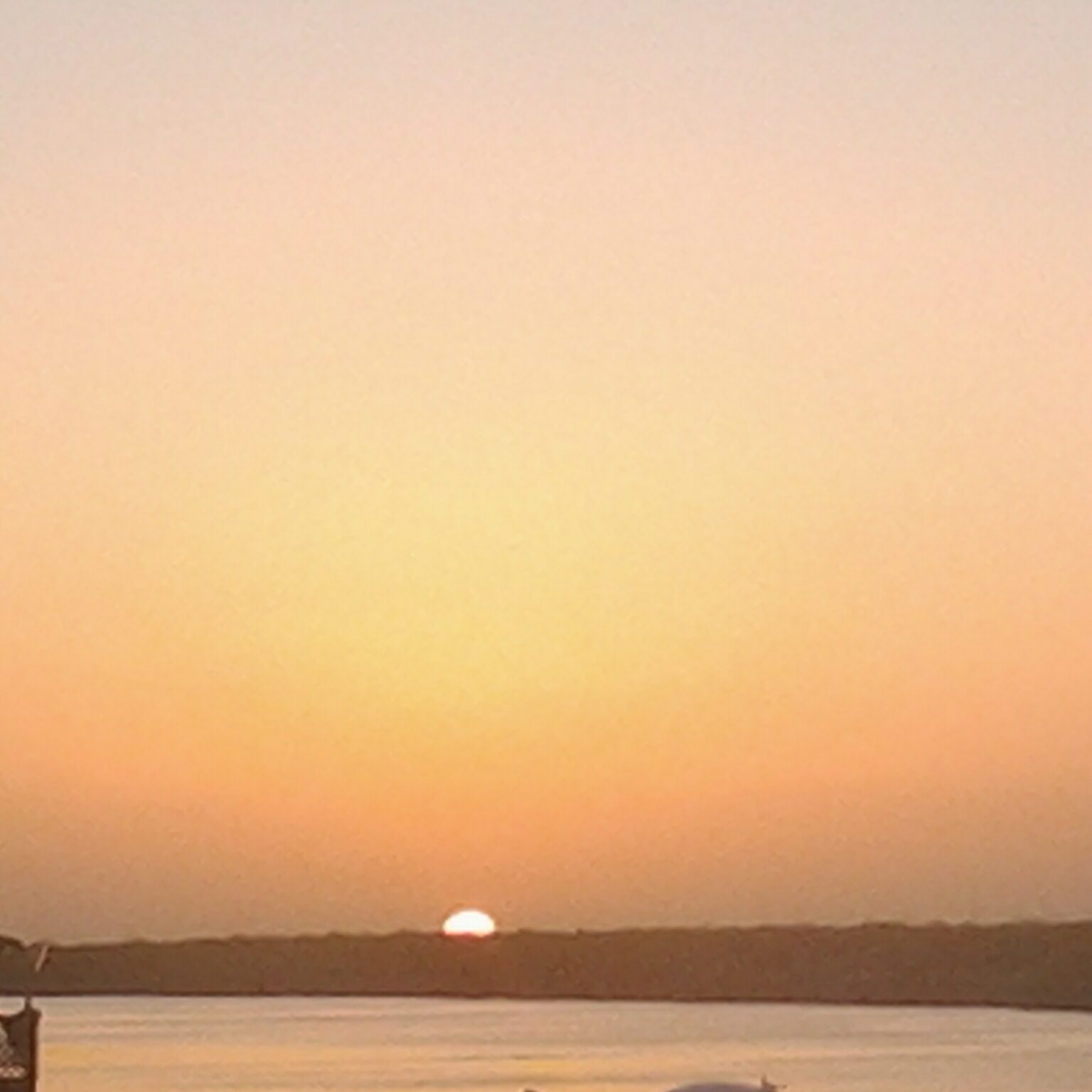 Sunset over calm water and distant horizon.