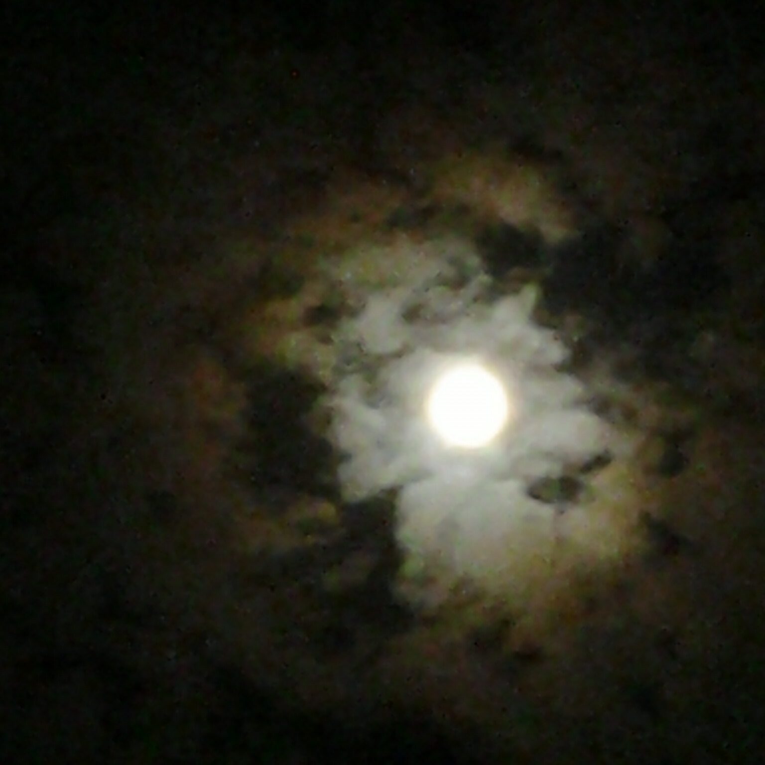 Moon surrounded by dark, cloudy sky.