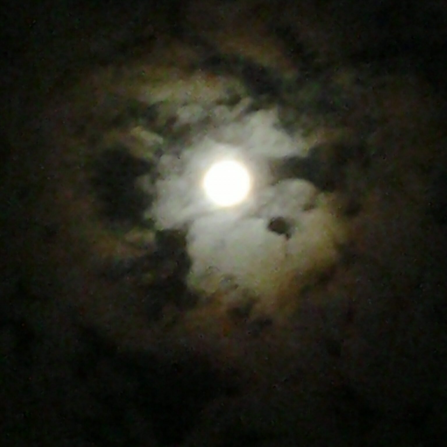 Full moon surrounded by swirling dark clouds.