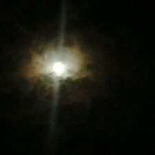 Moon shining through dark, cloudy night sky.