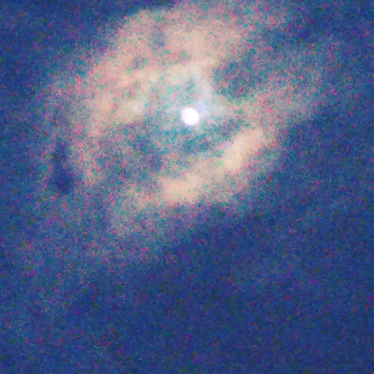 Moon surrounded by clouds in night sky.
