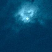 Moon obscured by cloudy night sky.