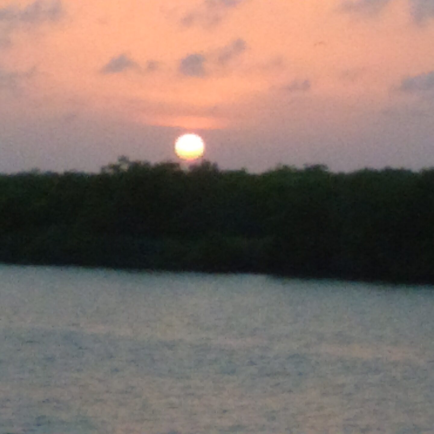 Sunset over calm water with clouds.