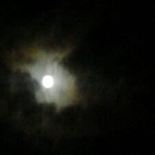 Full moon partially obscured by clouds.