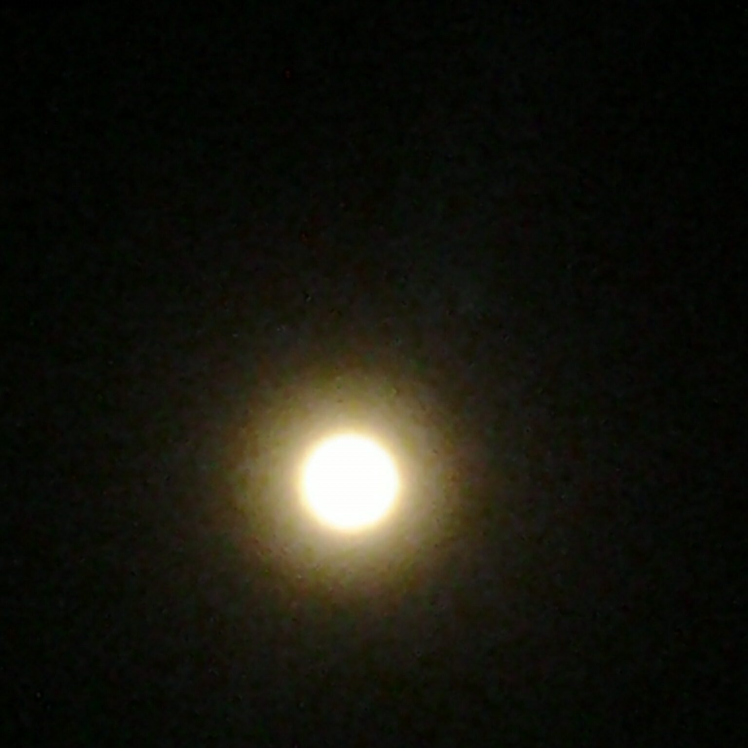 Bright full moon in dark night sky.