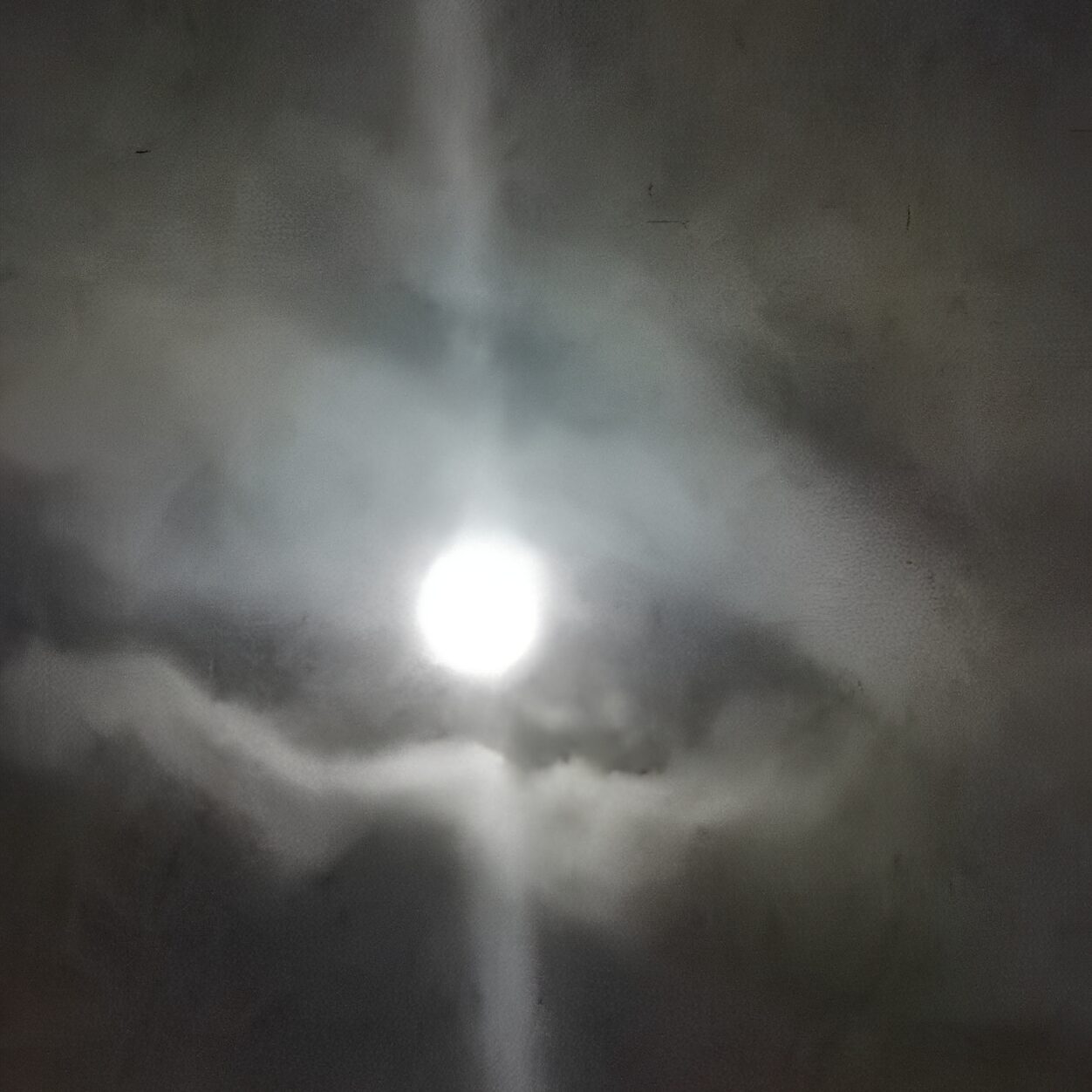Bright moon surrounded by clouds at night.