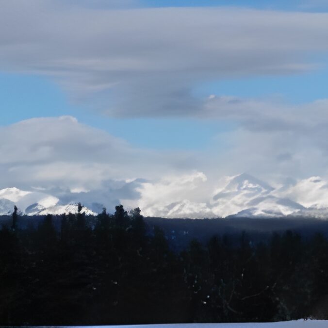 Snowy mountains under a cloudy blue sky.