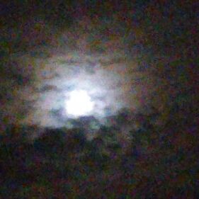 Moon behind clouds in a dark sky.