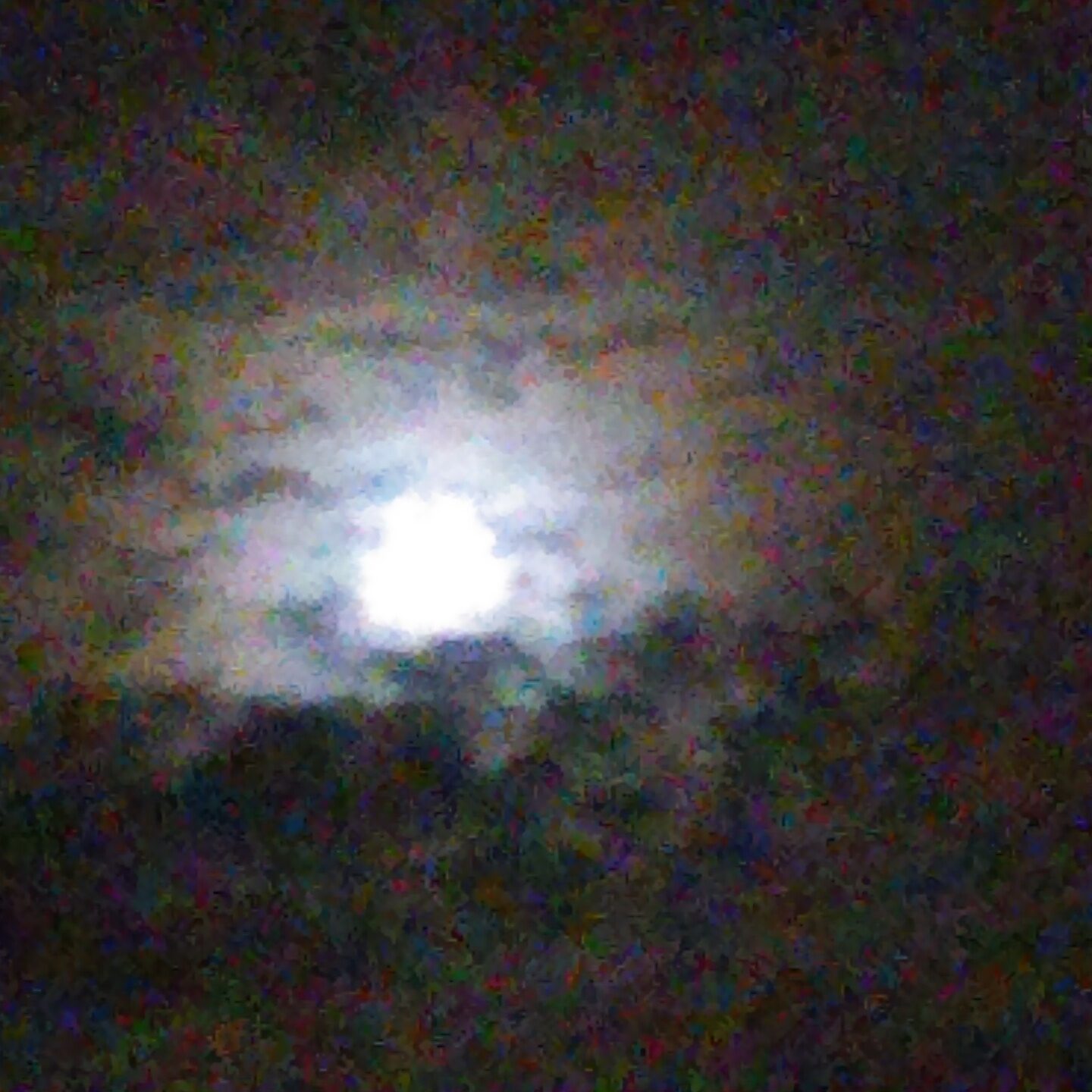 Full moon behind cloudy night sky.