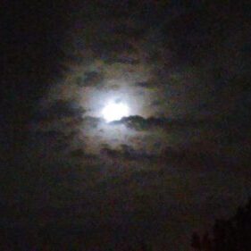 Moon shining through cloudy night sky.