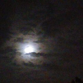 Moon shining through cloudy night sky.