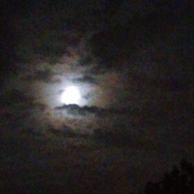 Moon shining through cloudy night sky.