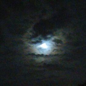 Cloudy night sky with glowing moon.