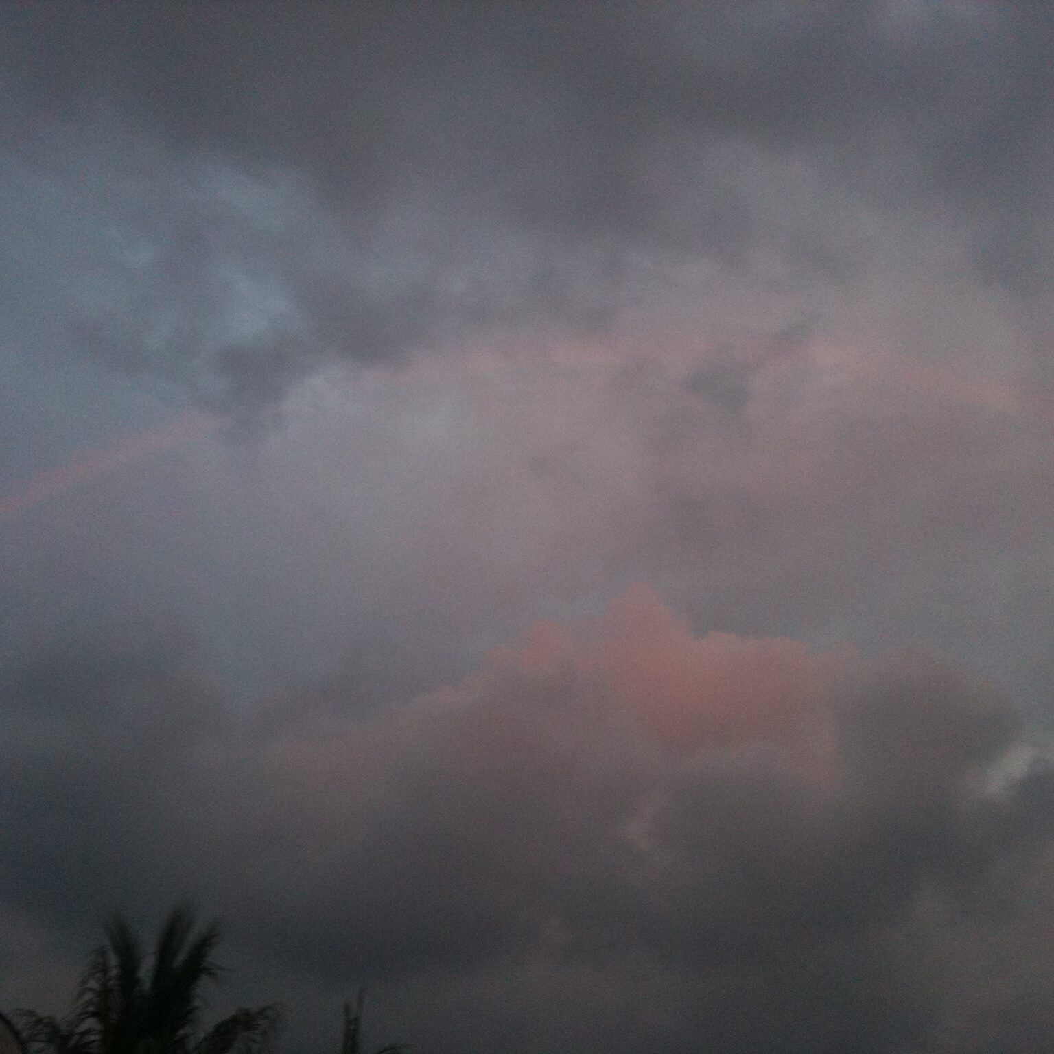 Faint rainbow in cloudy evening sky.