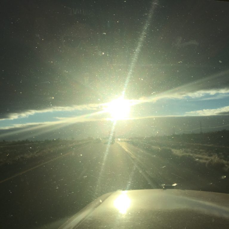 Sunny road view through car windshield.