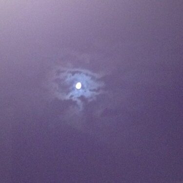 Moon surrounded by clouds in night sky.