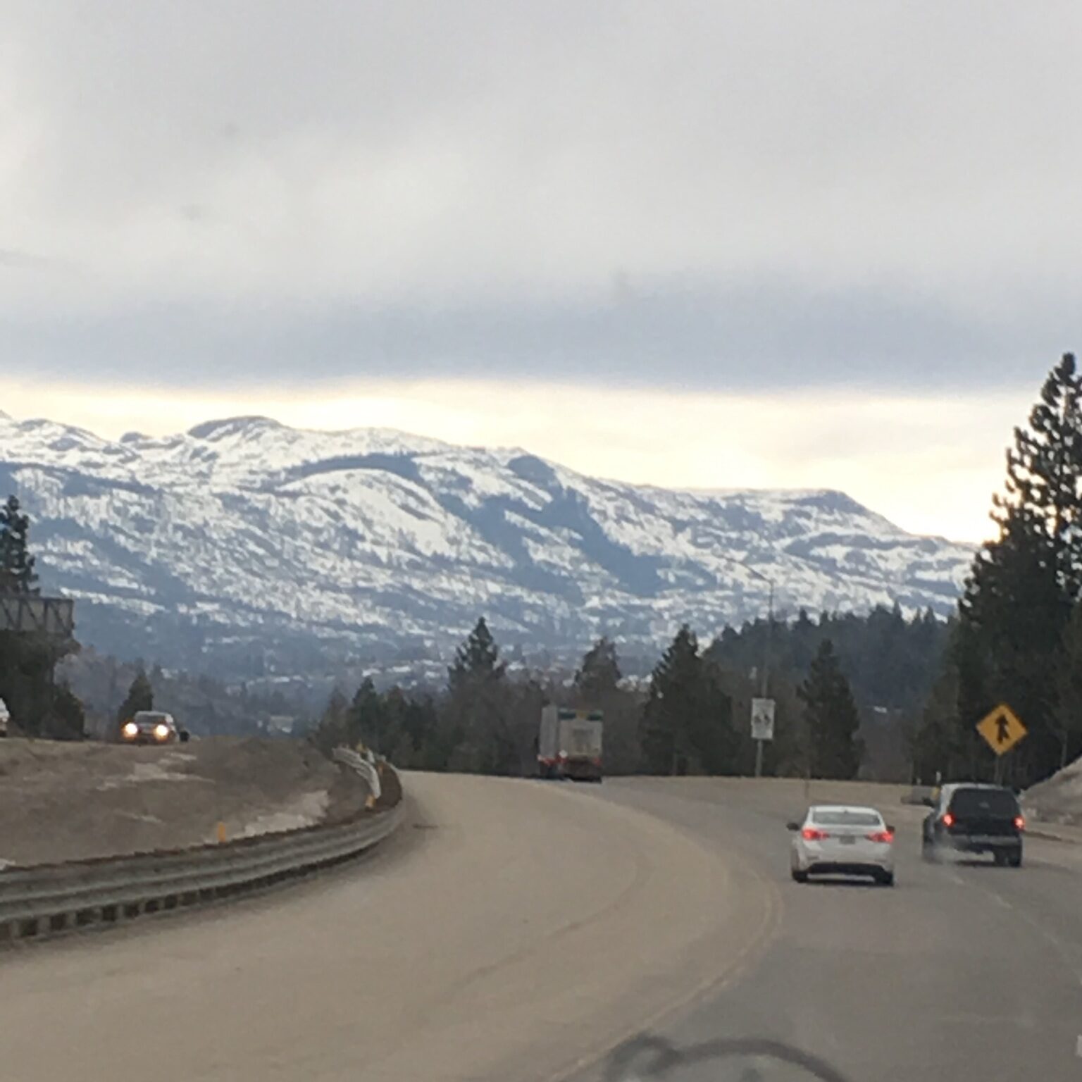 Mountain road with cars and snowy peaks.